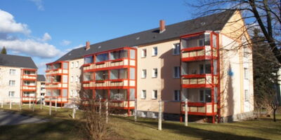 Mehrgeschossiges Wohnhaus mit heller Fassade und markanten roten Balkonkonstruktionen aus Stahl