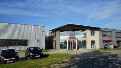 Modernes Gewerbegebäude mit großer Glasfassade, roten Akzenten und Metallverkleidung im Gewerbegebiet