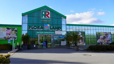 Eingangsbereich des Gartencenters Floraland von Gebrüder Roth mit grüner Glasfassade und Willkommensschrift